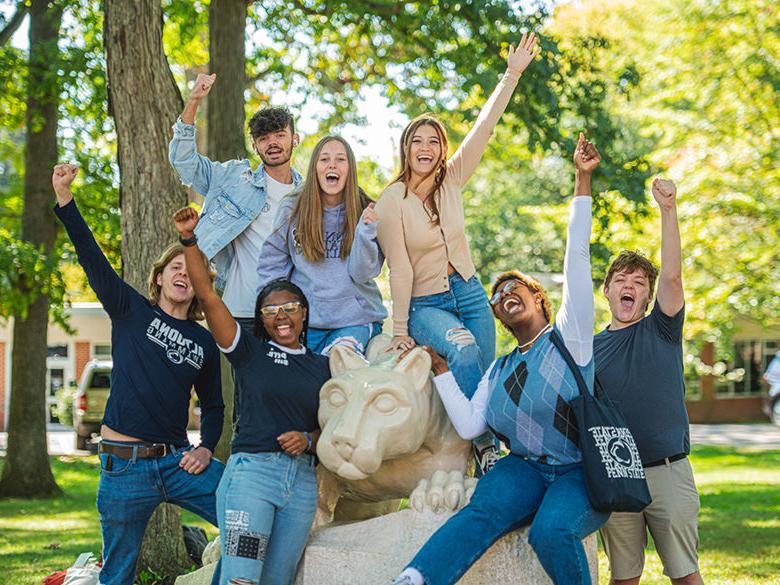 Several students cheering around the Lion Shrine